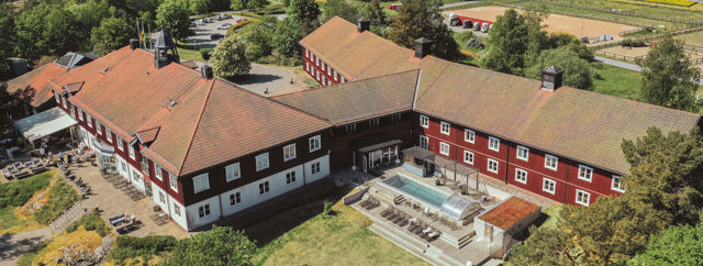 Överblicksbild över hotellet och utomhuspoolen som är inramat av vacker natur